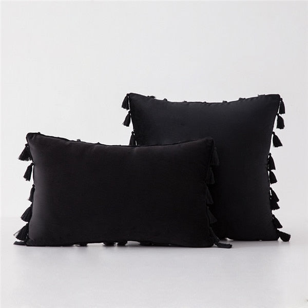 Two black pillows with tassels on a white background
