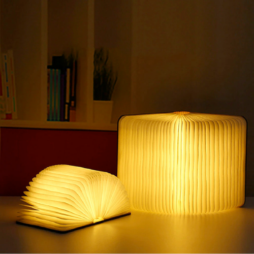 Two glowing book-shaped lamps on a surface with a blurred background