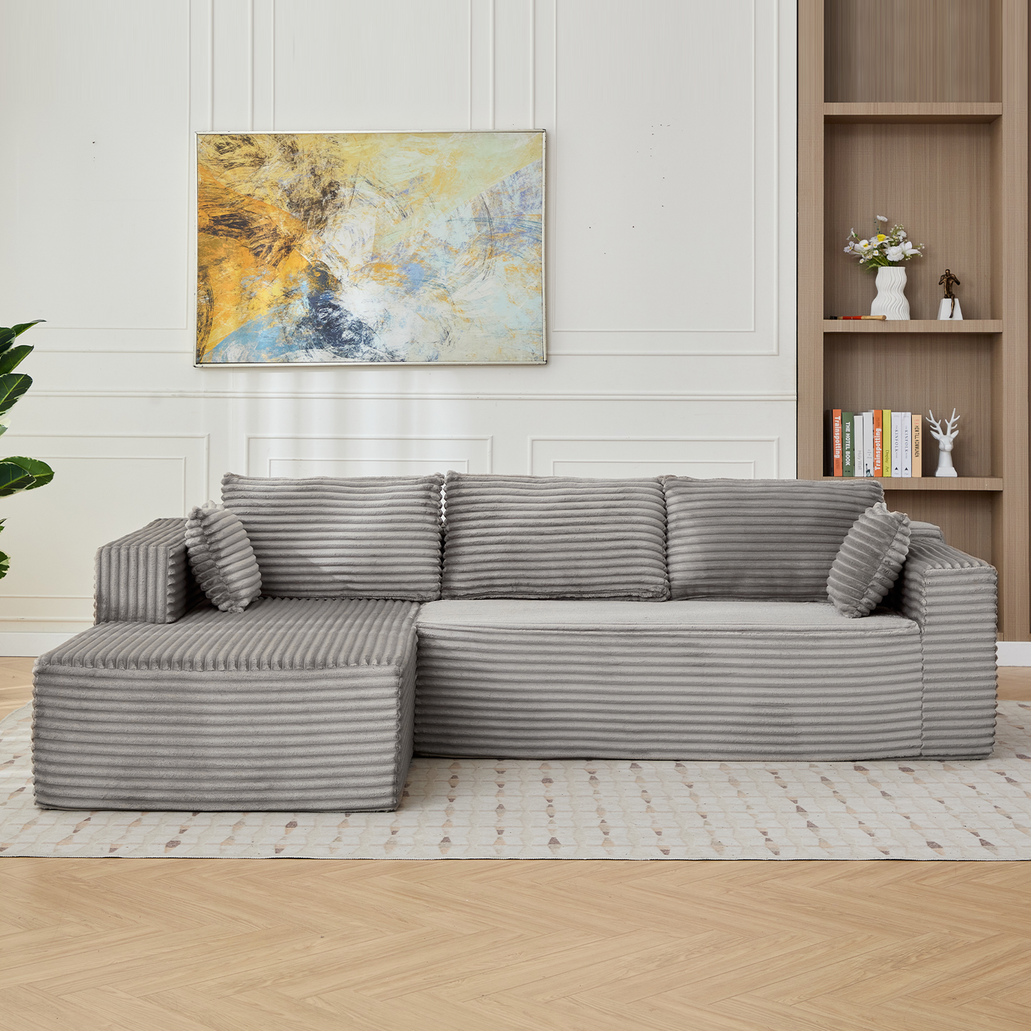 Gray sectional sofa in a living room with a painting and bookshelf in the background.
