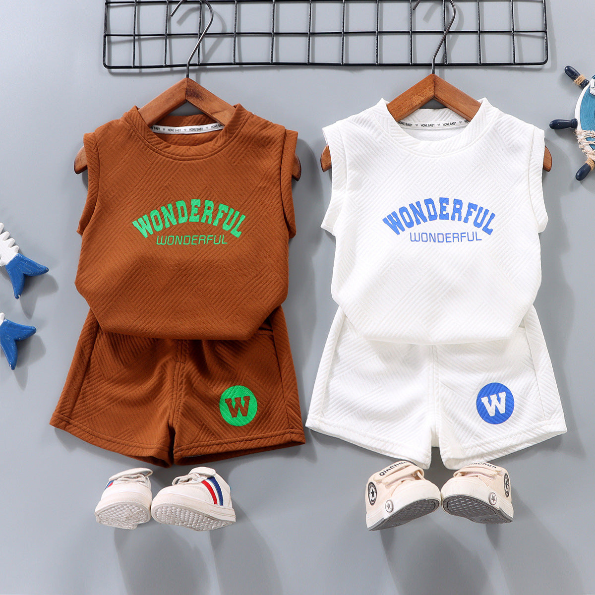 Two children's outfits with 'WONDERFUL' text on shirts, hanging on a rack.