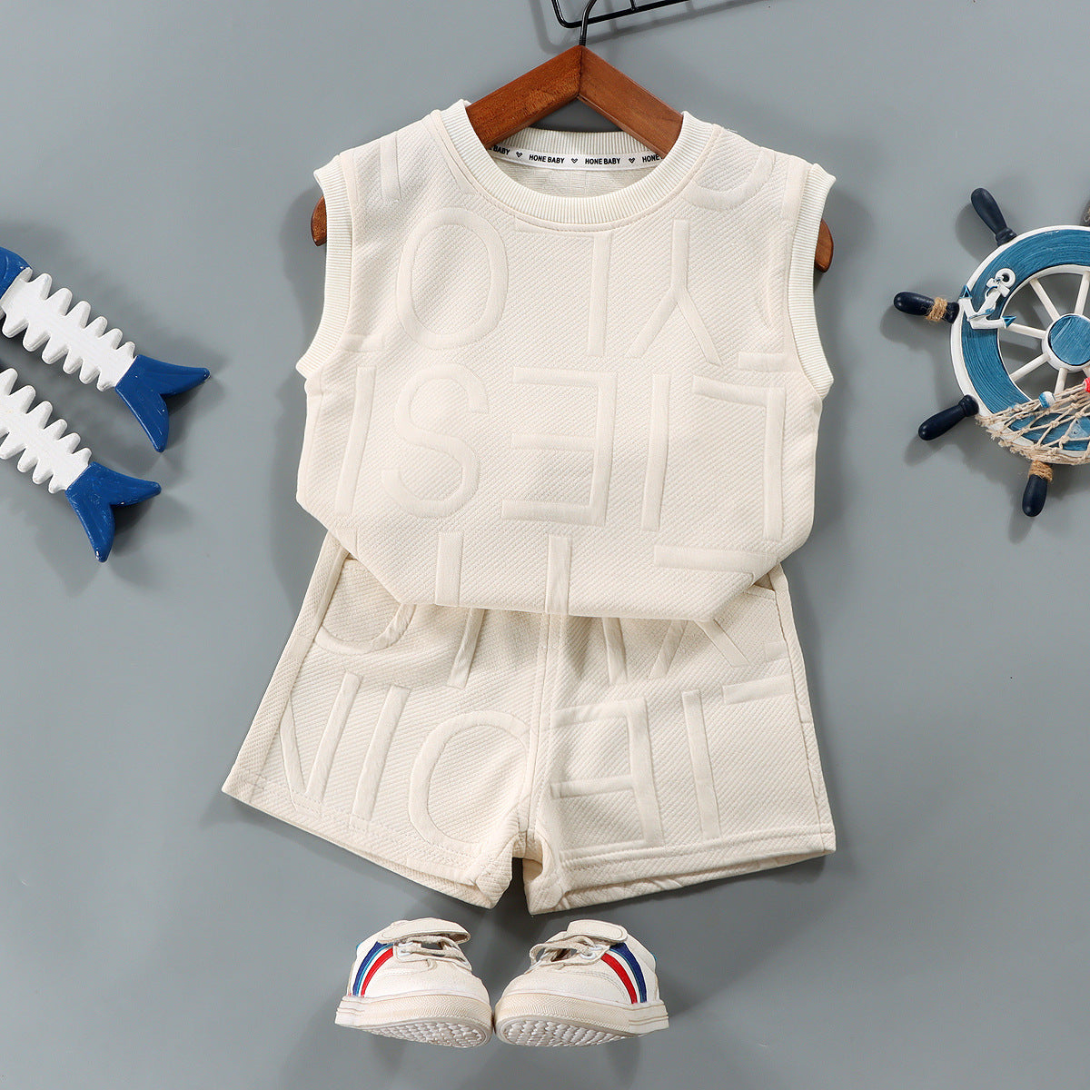 Children's white sleeveless top and shorts set with shoes on a gray background
