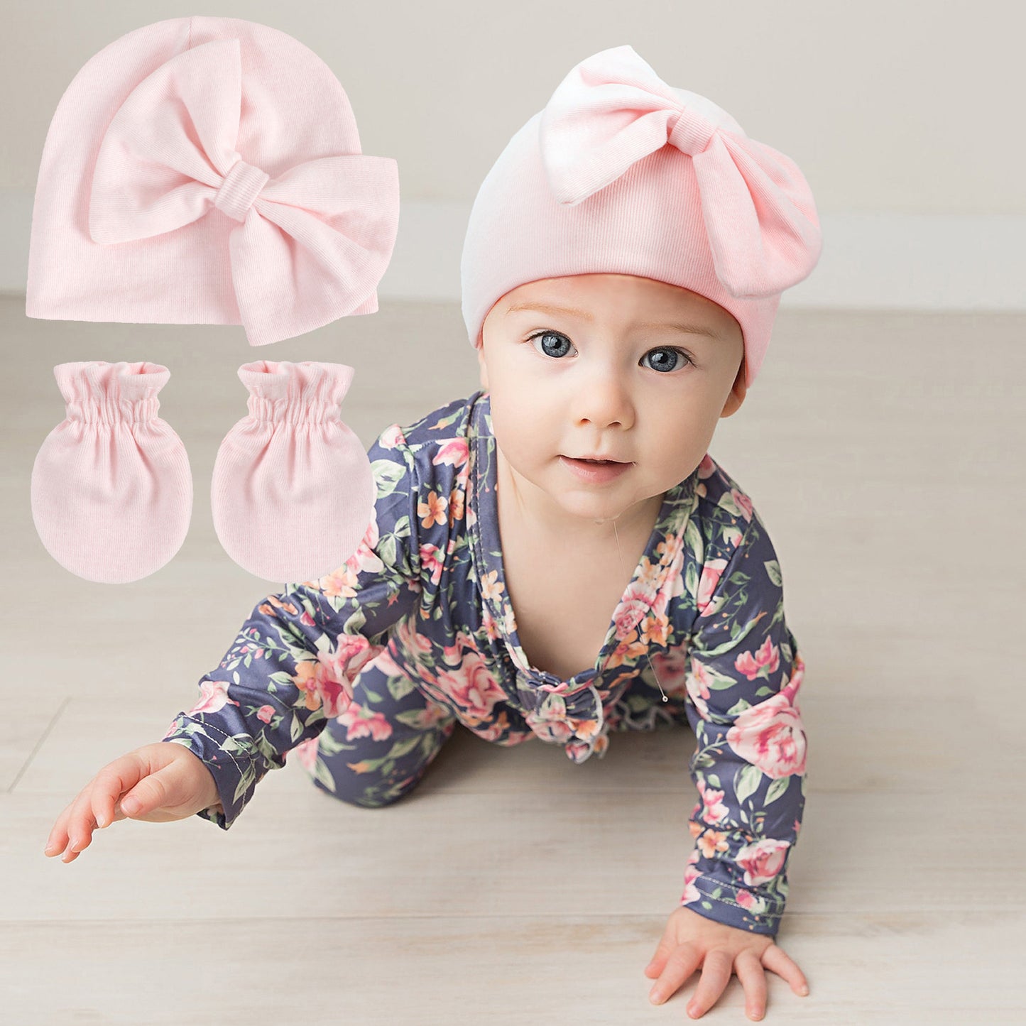 Baby wearing a floral outfit with pink headband and mittens on a light background