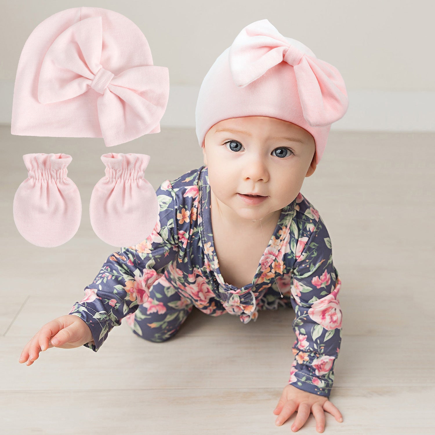 Baby wearing a floral outfit with pink headband and mittens on a light background