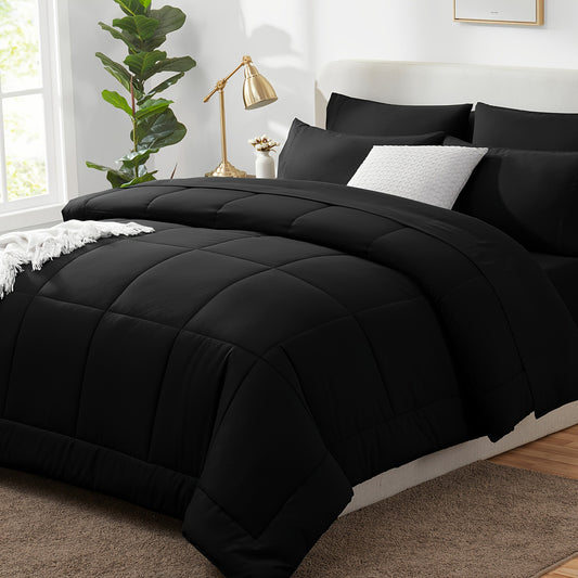 Black quilted comforter set on a bed in a bedroom with a lamp and plant.
