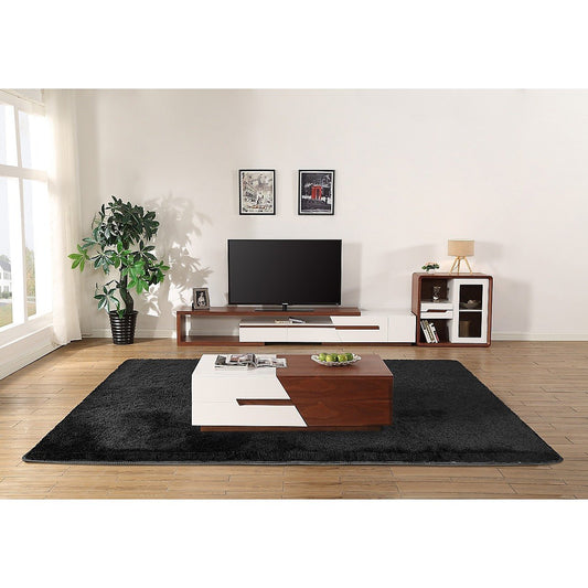 Modern living room with a black rug, wooden coffee table, and TV stand.