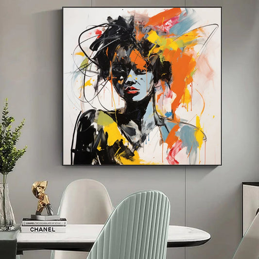 Abstract painting of a woman's face on a wall above a table with decor items.