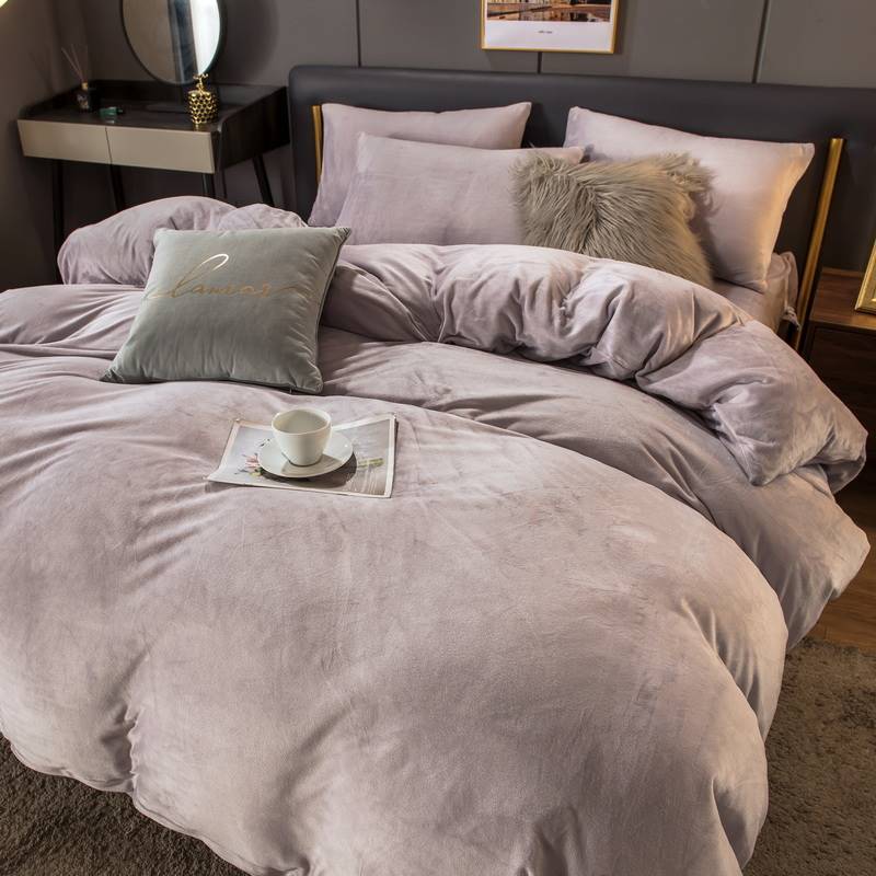Gray textured comforter set on a bed with pillows and a small tray with a cup.