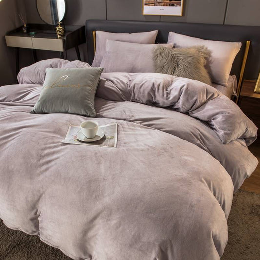 Gray textured comforter set on a bed with pillows and a small tray with a cup.