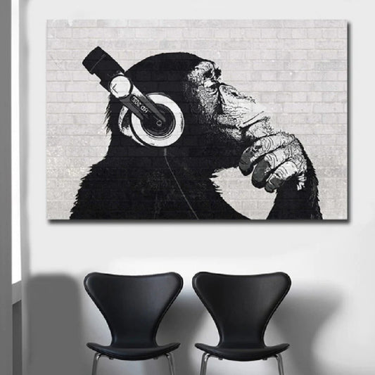 Canvas print of a chimpanzee wearing headphones against a brick wall with two black chairs below.