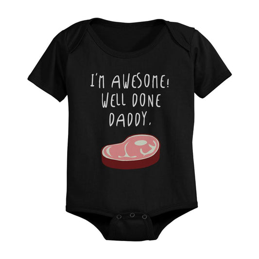 Black baby onesie with text 'I'm awesome! Well done daddy.' and a graphic of a steak on a white background.
