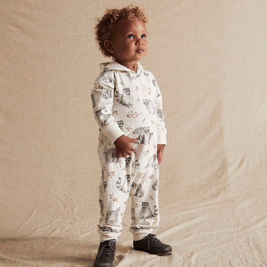 Child wearing a patterned onesie standing on a beige background